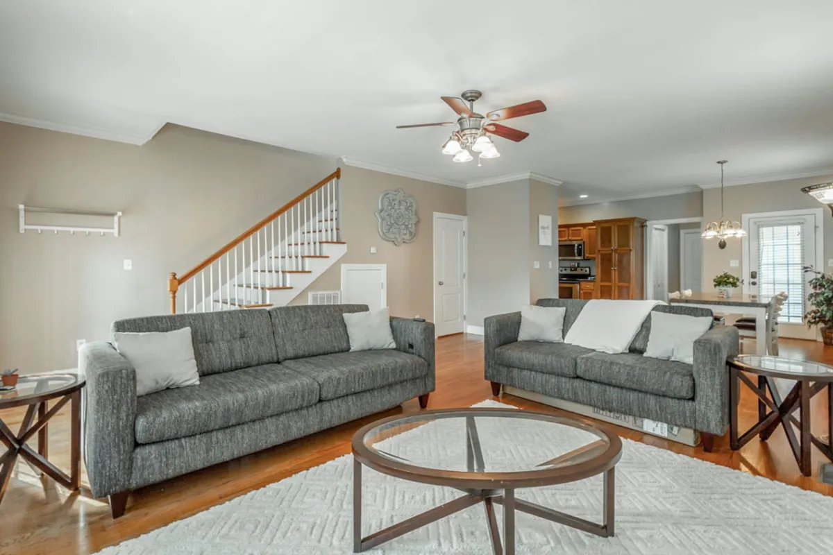 A comfortable entry-level living space with plush sofas, a central coffee table, and a staircase leading further inside. The room creates an inviting atmosphere for relaxing or transitioning from outside to home.