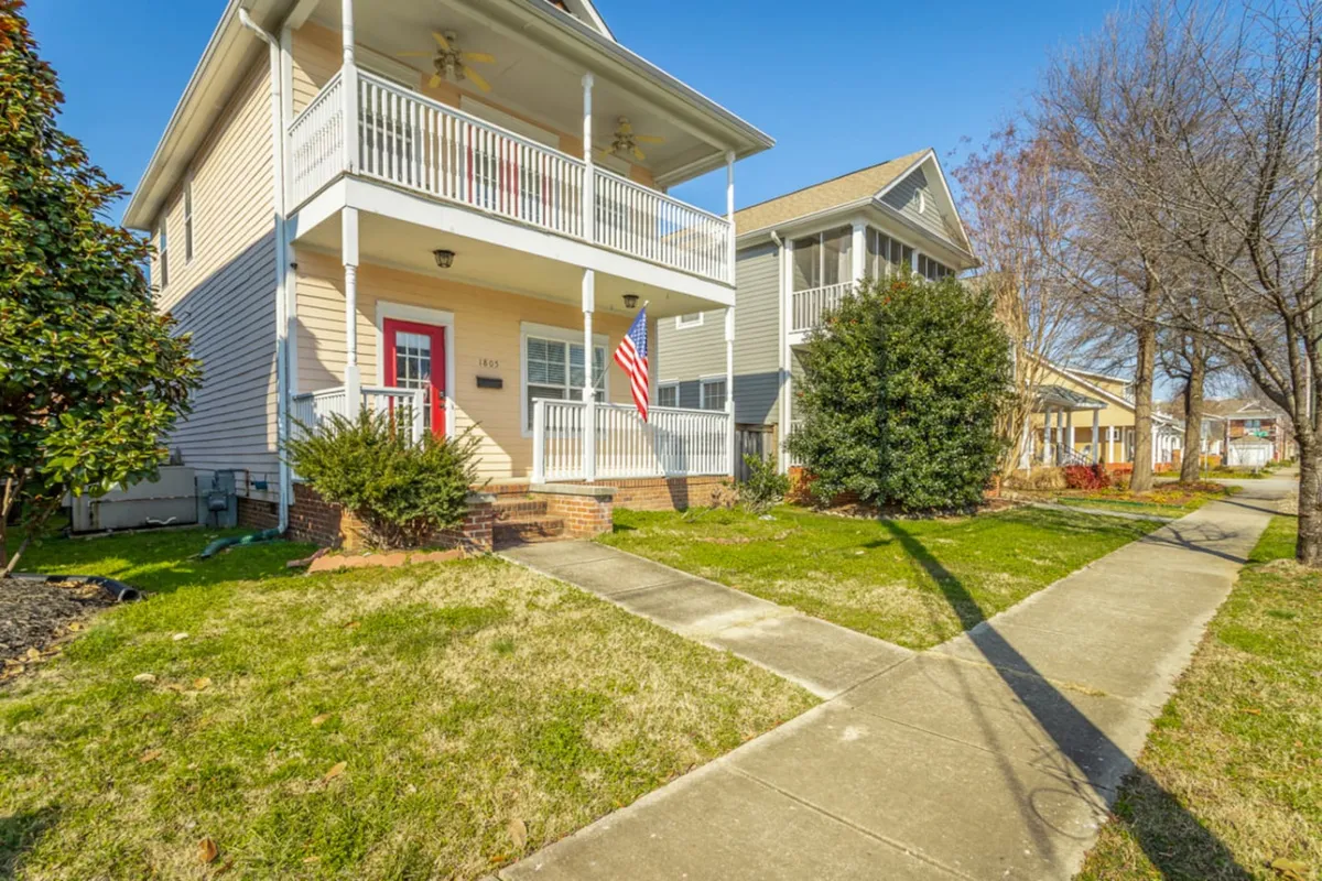 This image features the home's welcoming front porch adorned with a flag and surrounded by a landscaped yard. The inviting outdoor seating area suggests a place for families to relax after exploring local attractions, while the neatly kept exterior reflects a safe, comfortable neighborhood.