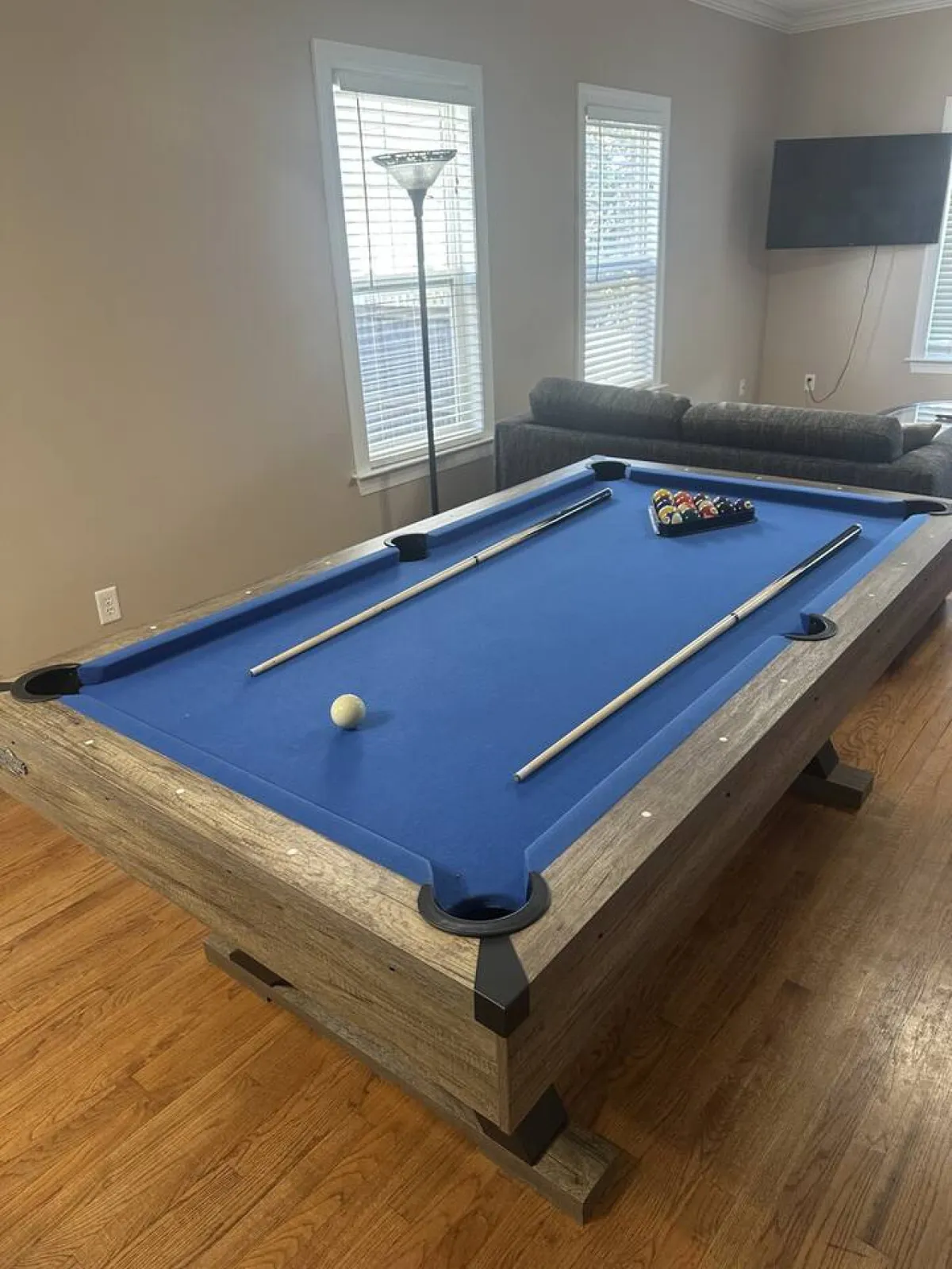 The interior scene includes a pool table, sofa, lamp, and television, capturing a space where guests can play games, socialize, and watch TV together. The mood is relaxed and fun, emphasizing communal experiences and leisure during a stay.