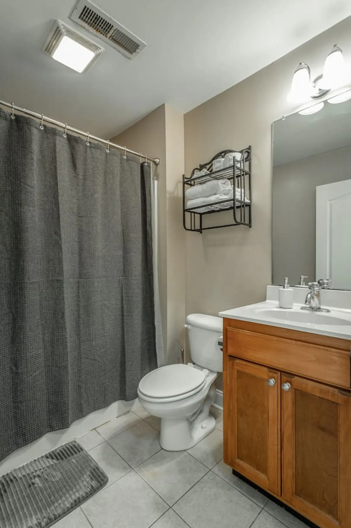 A modern bathroom scene featuring a clean vanity with sink, a neatly hung towel rack, a shower curtain, and a large mirror. The space is bright, organized, and offers all the essentials for a refreshing start or finish to the day.