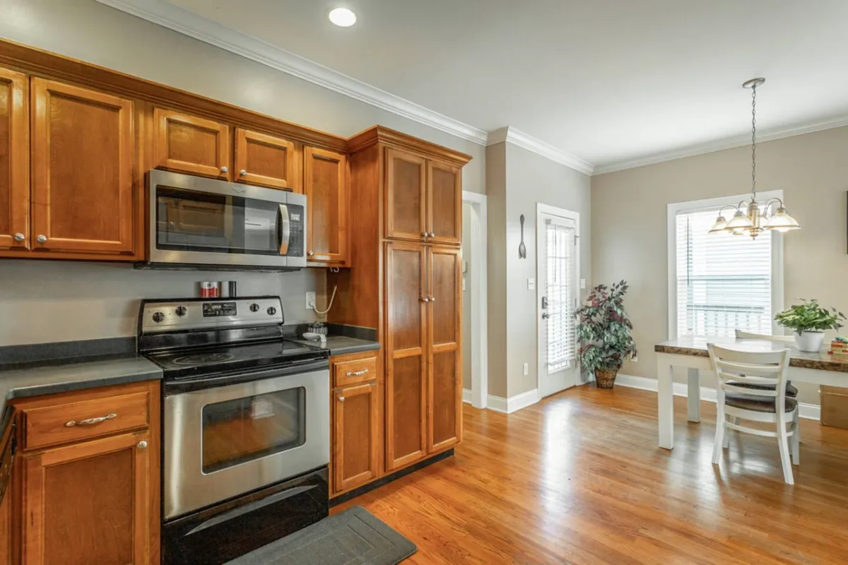 A bright, inviting kitchen with stainless steel appliances, rich wood cabinetry, and a charming breakfast nook. The layout encourages both cooking and casual dining, with space for socializing while preparing meals.