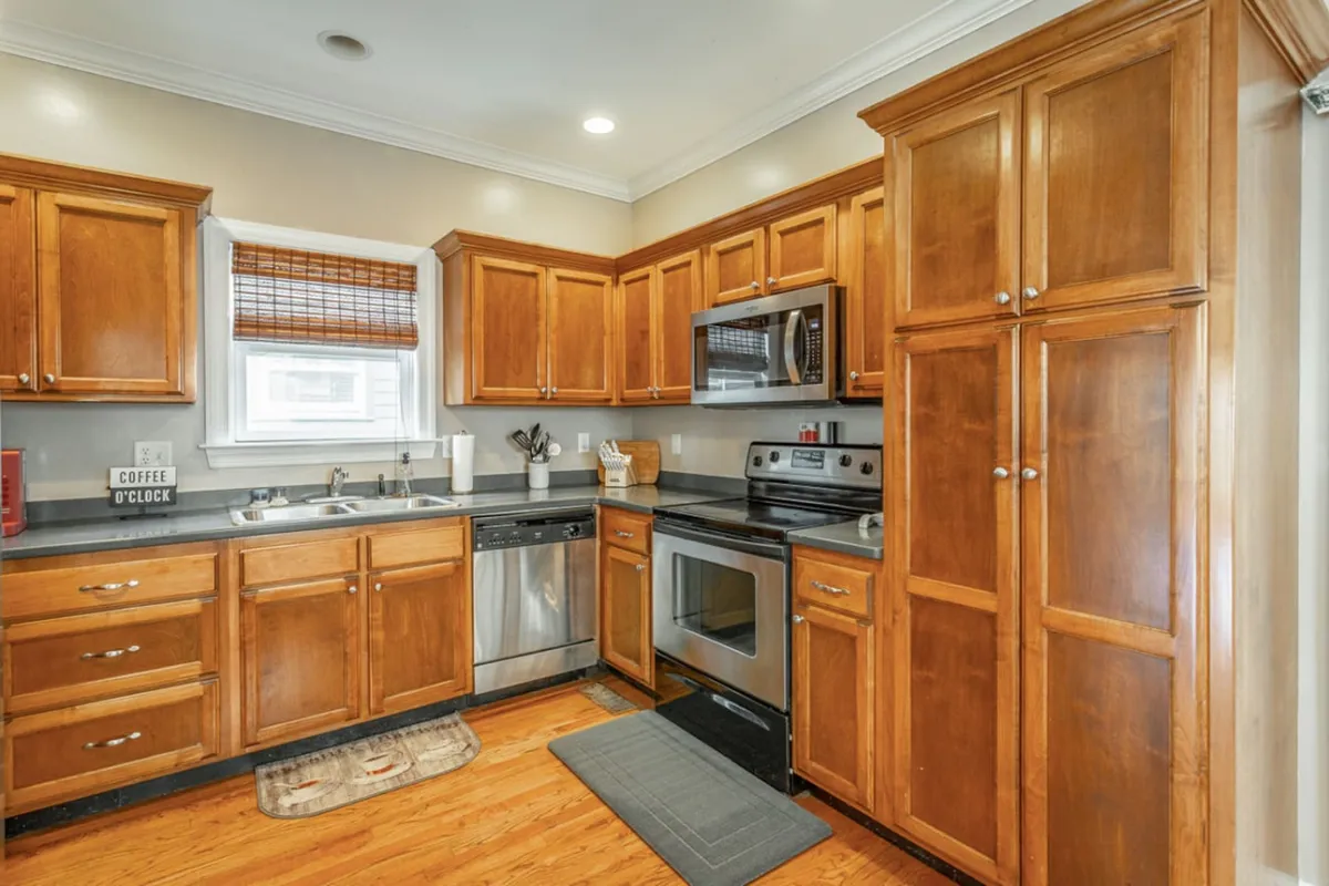 This image features a modern kitchen with wooden cabinets, up-to-date appliances, and a central kitchen island. The space is bright and well-organized, offering plenty of counter space for meal prep and group activities. The layout supports both ambitious cooking sessions and casual snacks.